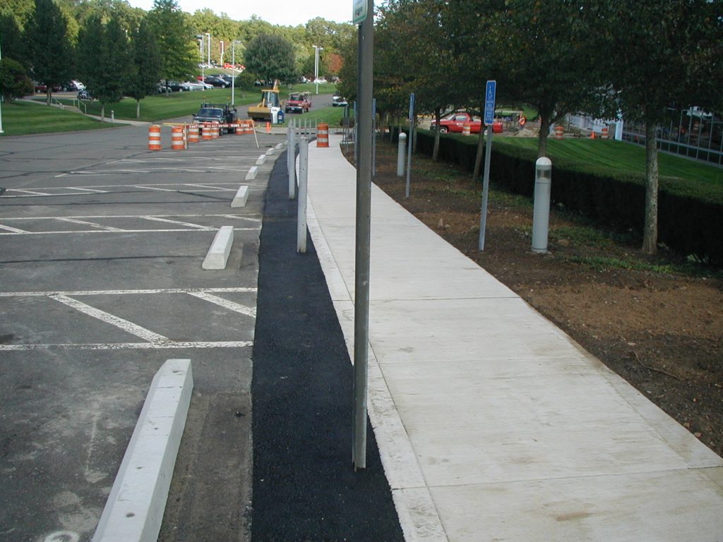 A concrete sidewalk with fresh asphalt